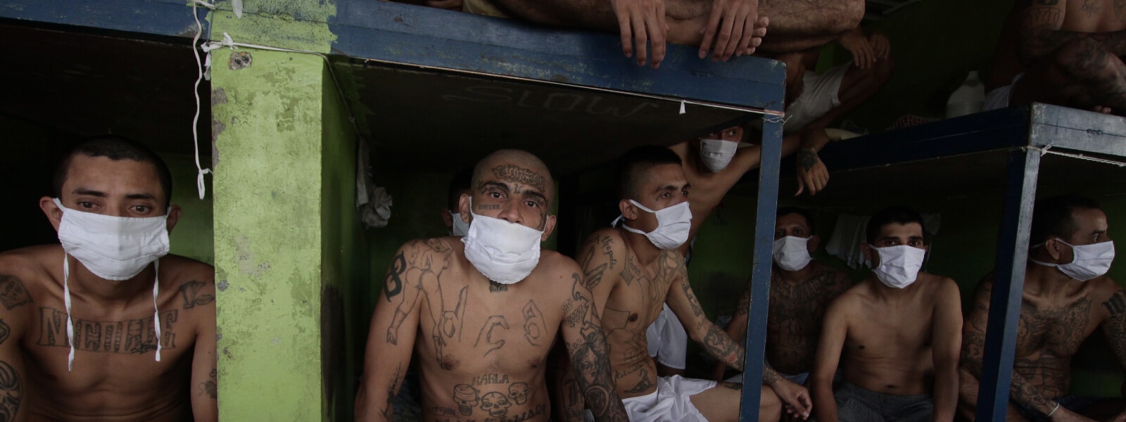 1.-El-Salvador_Imprisoned-gang-members-wearing-protective-face-masks-sit-inside-a-group-cell_AP_20335158061131_2020_Gamechangers.jpg